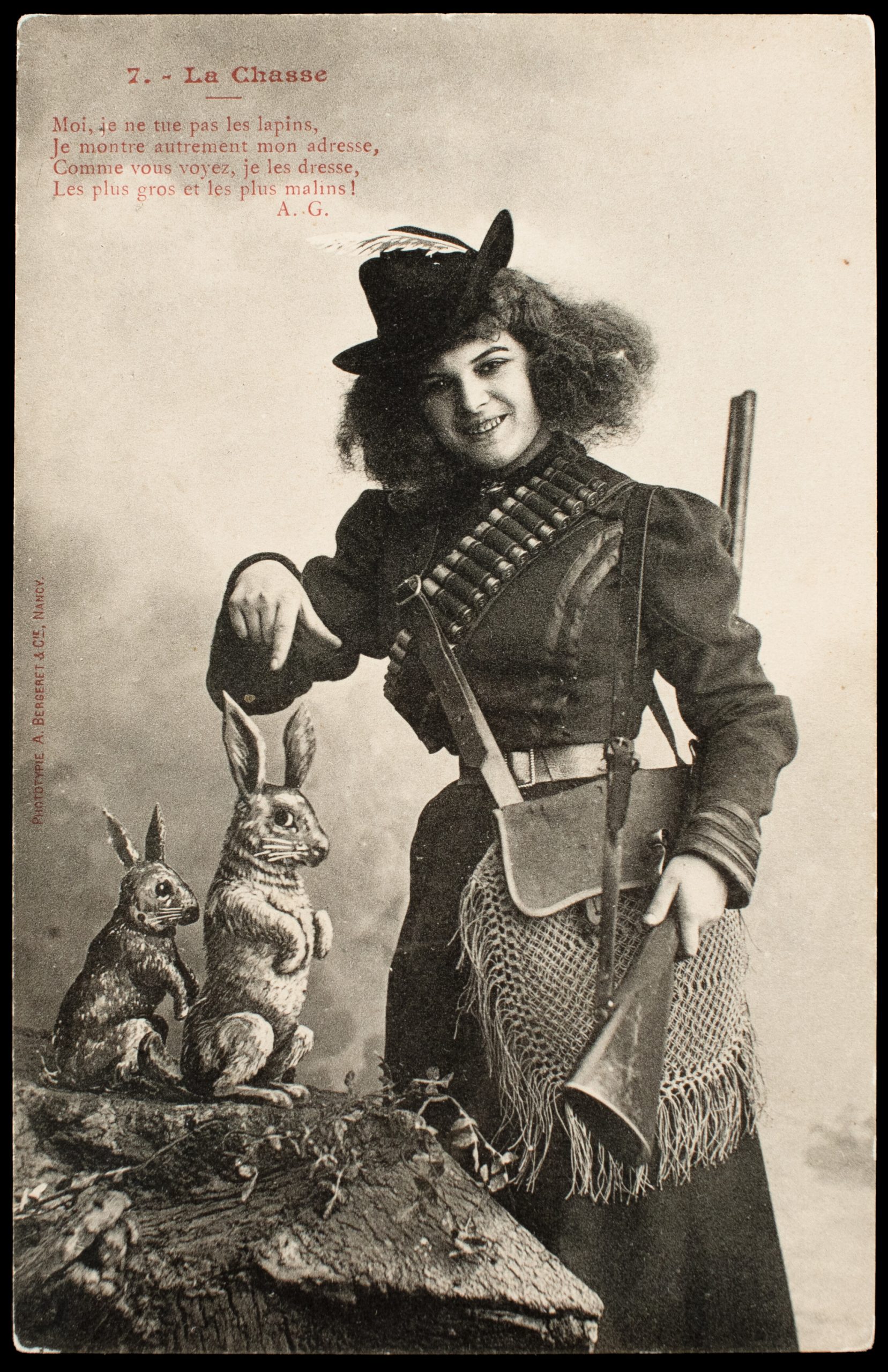 Comic French postcard showing a female hunter with pinfire shotgun, centerfire shotshell bandolier, and two posed rabbit props.